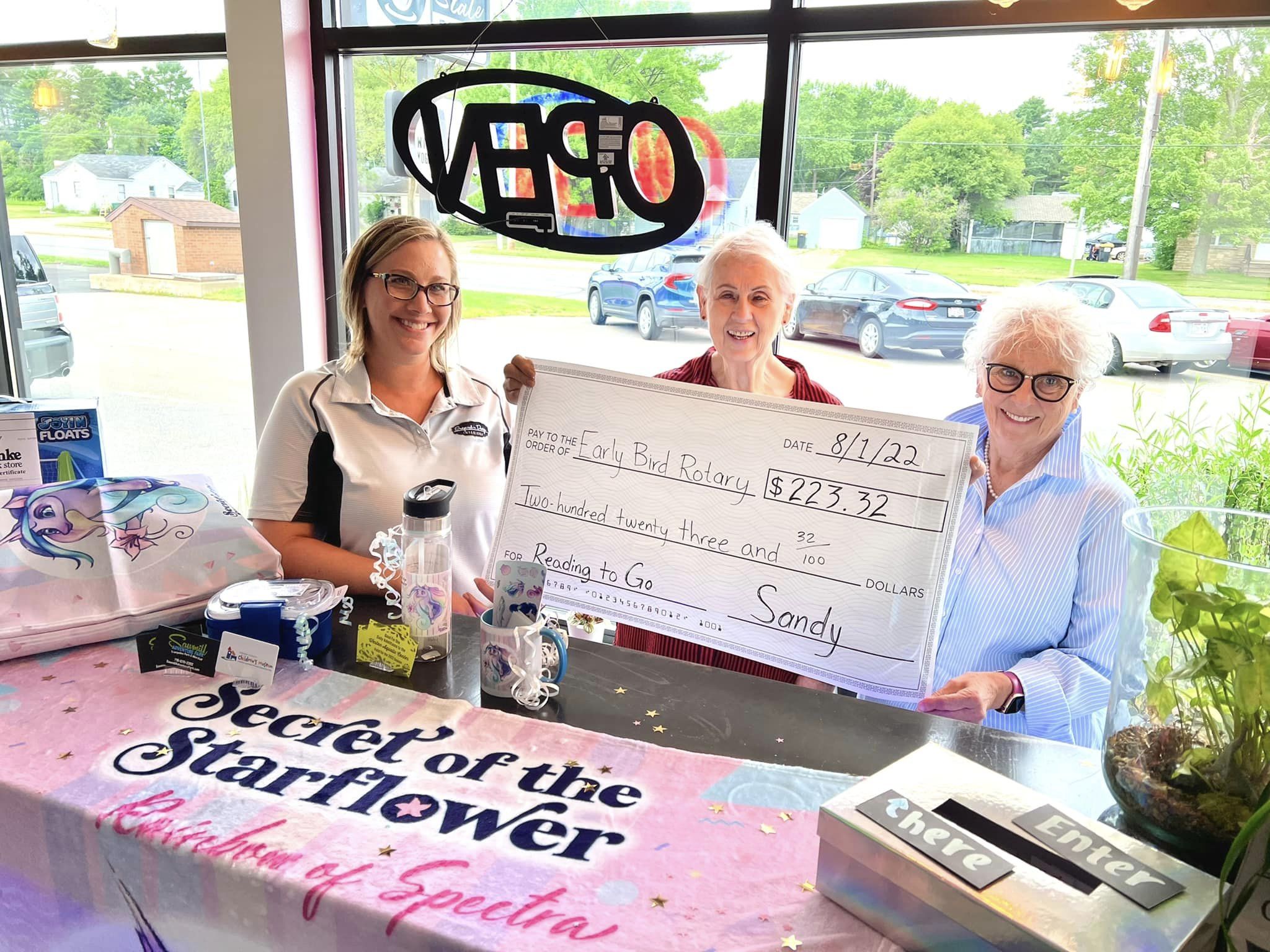 One of the two 2022 pledge sponsors, Sara Haumschild of Inspired by Design Interiors, presents a check to Wausau Early Bird Rotary representatives for their Reading to Go program.